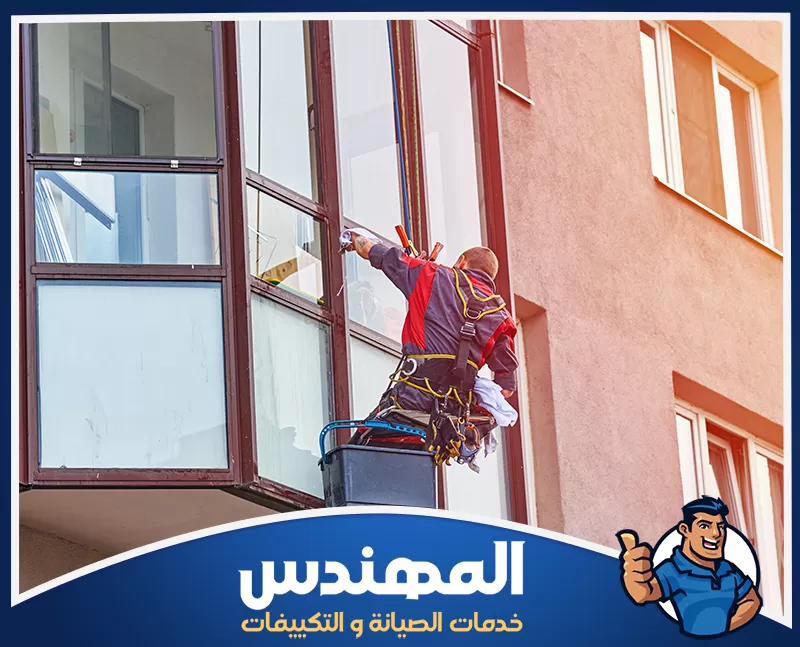 تنظيف واجهات محلات حفر الباطن 0546176127 شركة المهندس رجل ينظف نوافذ مبنى في حفر الباطن باستخدام أدوات خاصة لتنظيف الزجاج الخارجي.