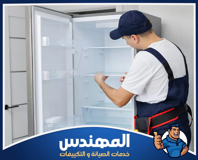 إصلاح الثلاجات في المنزل في حفر الباطن 0546176127 شركة المهندس رجل يرتدي بدلة زرقاء ينظر إلى ثلاجة مفتوحة، يظهر اهتمامه بصيانة الثلاجات في حفر الباطن.