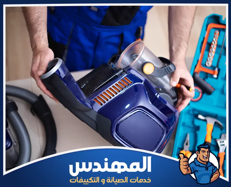 إصلاح موتور المكنسة في حفر الباطن 0546176127 شركة المهندس رجل يقوم بصيانة مكانس في حفر الباطن، ممسكًا بمكنسة كهربائية وأدوات أخرى.