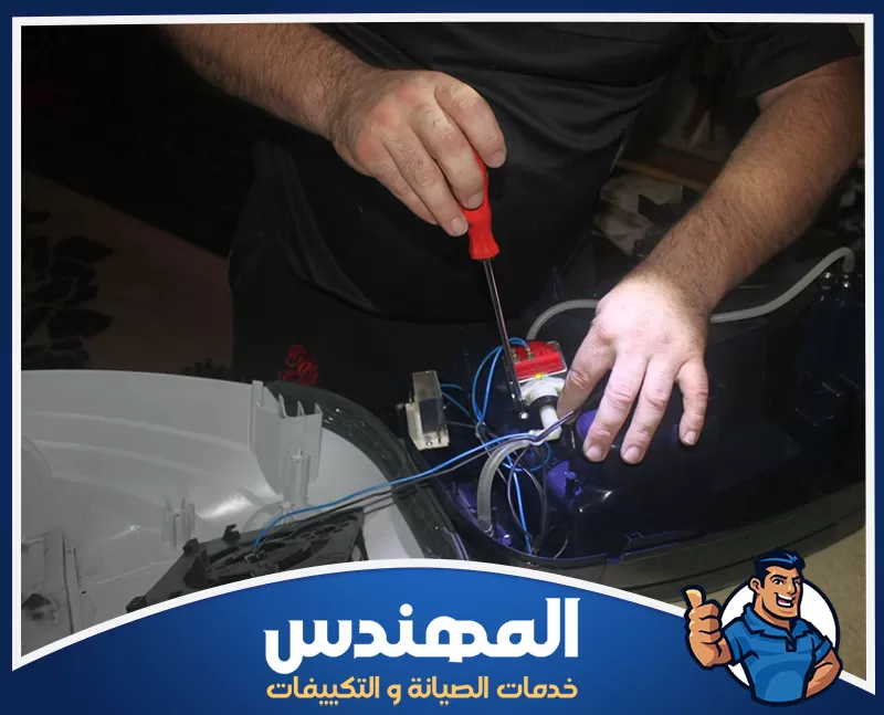 صيانة مكنسة كهربائية في حفر الباطن 0546176127 شركة المهندس رجل يقوم بإصلاح مكنسة باستخدام مفك، في ورشة صيانة مكانس بحفر الباطن.