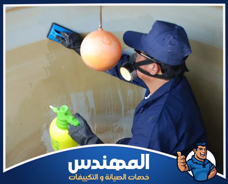 تنظيف خزانات خرسانية في حفر الباطن 0546176127 المهندس فني يرتدي معدات حماية وينظف الجدار الداخلي لخزان مياه باستخدام أداة تنظيف وعبوة رش مخصصة.