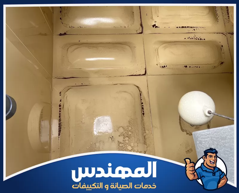شركة تنظيف خزانات في حفر الباطن 0546176127 المهندس خزان مياه تظهر بداخله رواسب وبقع داكنة متراكمة عند الجدران والزوايا، مع وجود عوامة للتحكم في مستوى المياه.