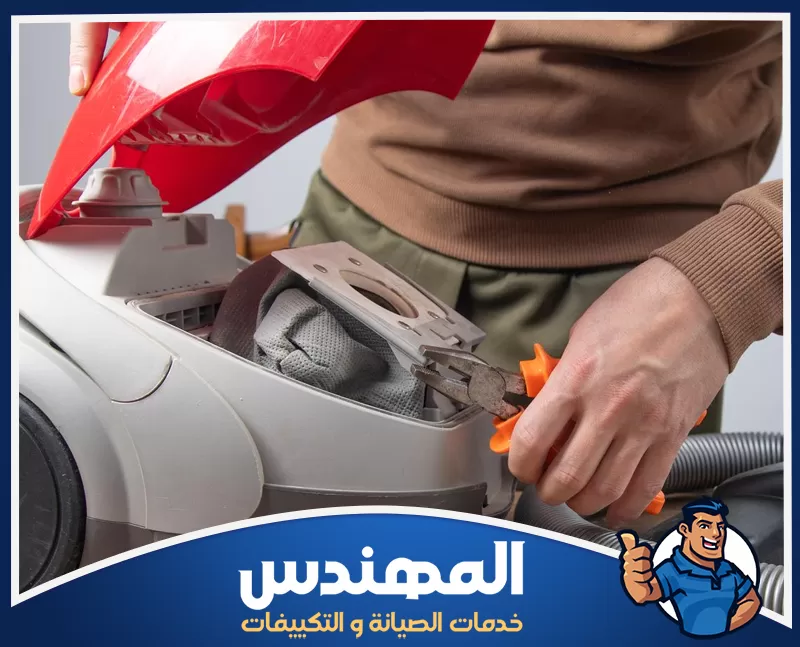 شركة صيانة الاجهزة الكهربائية بحفر الباطن 0546176127 المهندس للصيانة فني يقوم بعملية صيانة داخلية لجهاز مكنسة كهربائية بعد فتحها، حيث يعمل على إصلاح أو فحص الأجزاء الداخلية باستخدام أدوات صيانة.