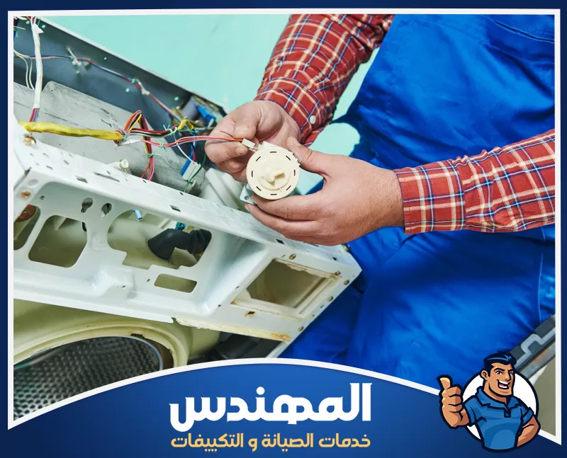 شركة صيانة غسالات بحفر الباطن 0546176127 المهندس فني يفحص أحد المكونات الكهربائية داخل غسالة أثناء أعمال الصيانة والإصلاح.