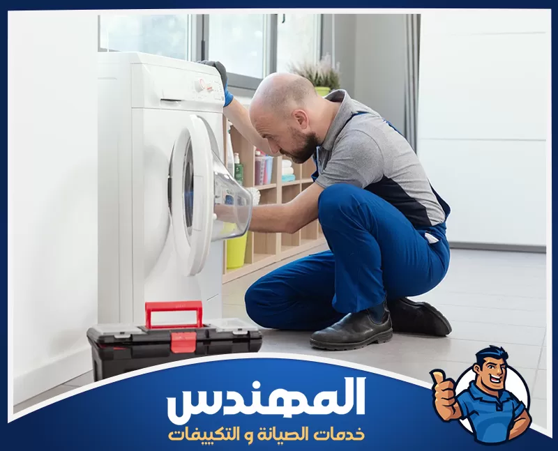 فني صيانة يفحص غسالة أمامية ويعاين درج المنظفات لتحديد سبب العطل.
